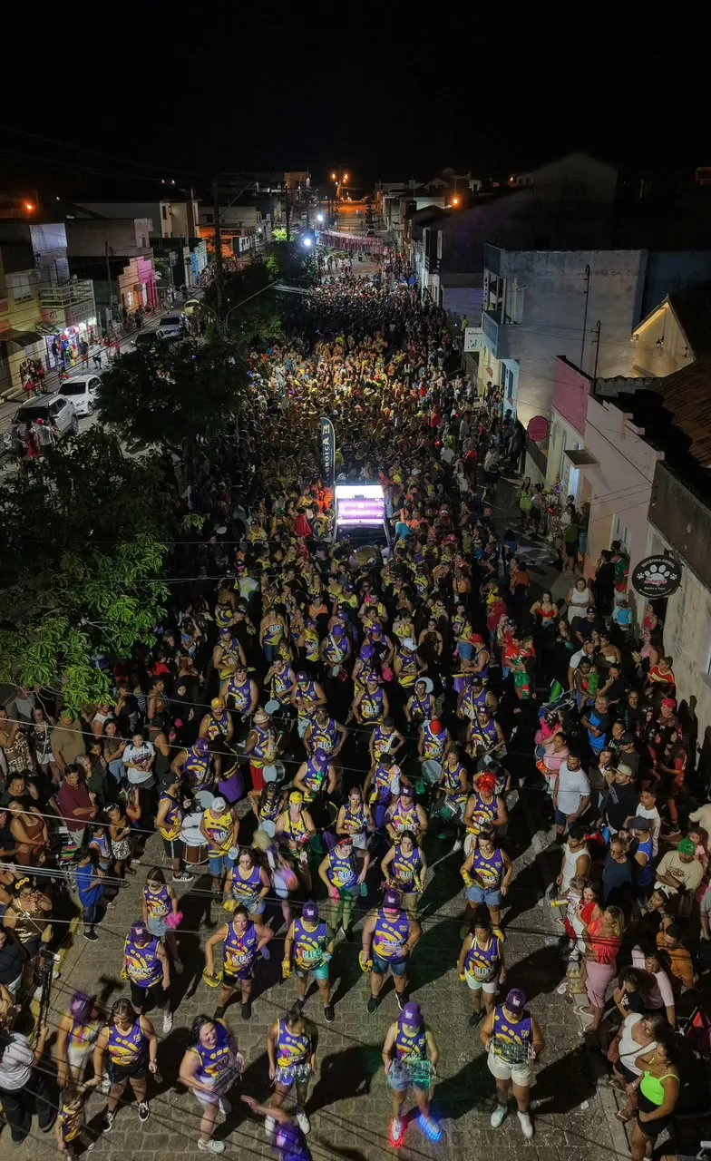 Vista de cima do desfile: a bateria de abadá roxo e amarelo e a rua lotada